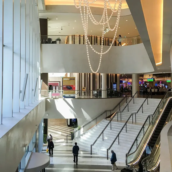 Intérieur du Parq Vancouver : un escalier de marbre et des escaliers mécaniques sous un lustre en chaînes, menant à la salle de jeu